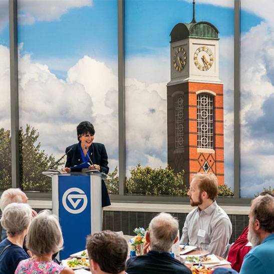 President Mantella speaks to a crowd, an image of the Carillon Tower is behind her